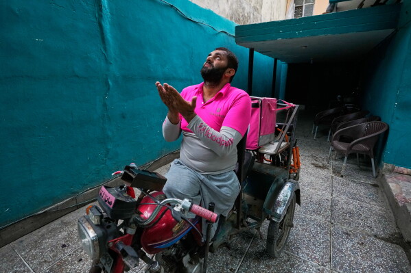 Hamza Ali, 28, who lost both legs in a road accident, prays before leaving for work in Islamabad, Pakistan, Friday, July 17, 2026. (AP Photo/Anjum Naveed)
