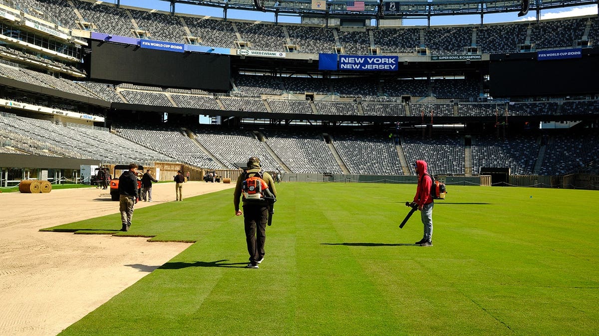 Workers installing the pitch at New York New Jersey Stadium in East Rutherford