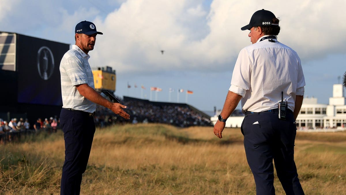 Bryson DeChambeau speaks to a rules office before a shot on the 18th hole.