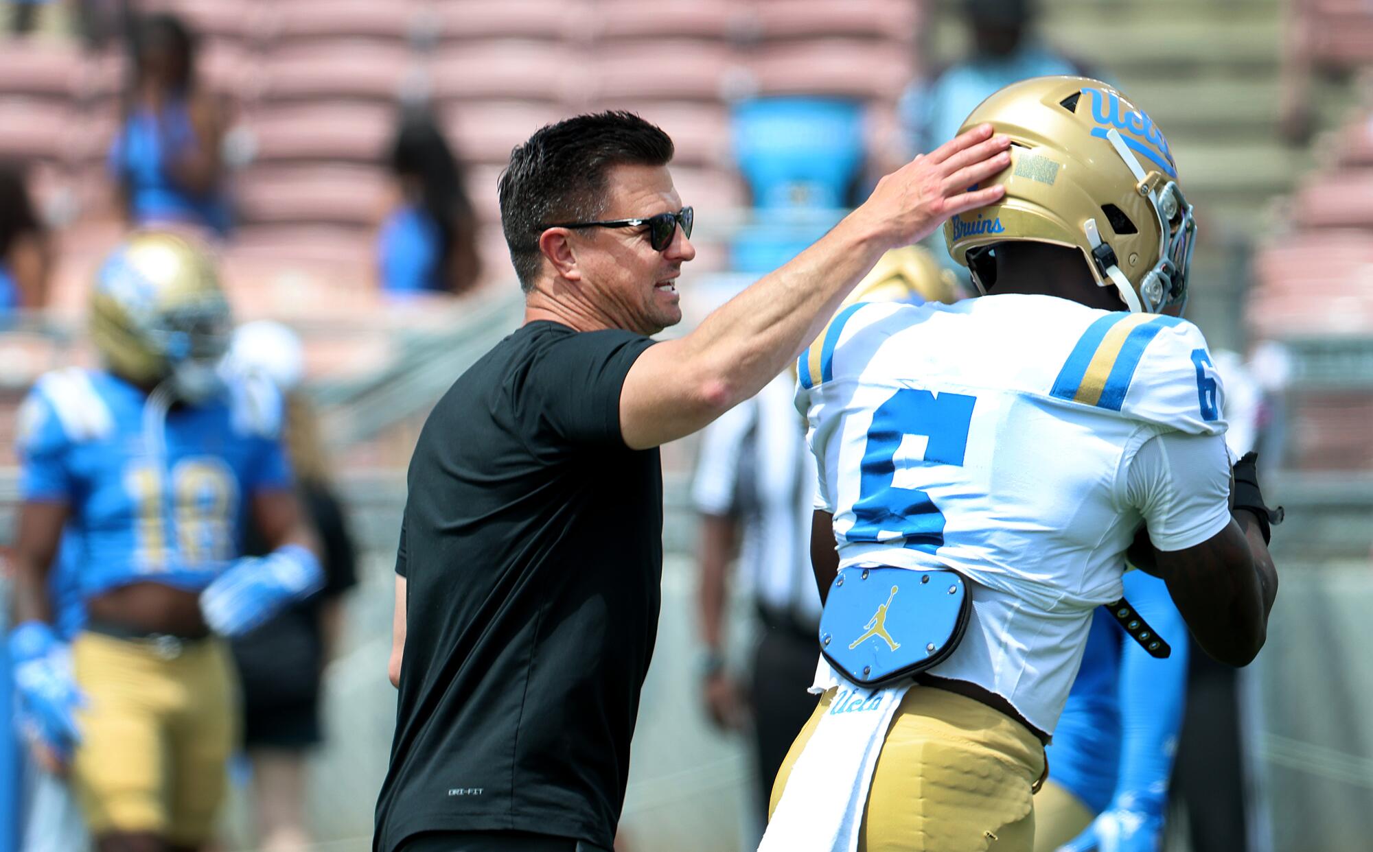 UCLA coach Bob Chesney pats running back Anthony Woods on the helmet during the team's spring game at the Rose Bowl.