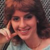 This photo shows Susan Greenstein Prescott when she was an adolescent. Photographed from about the shoulders up, she's wearing a light blue sweater and is smiling.