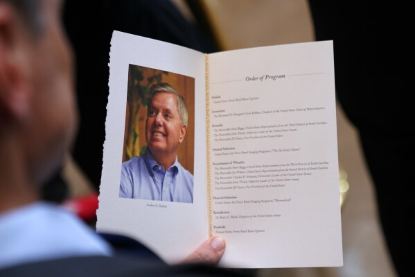A guest looks at the program during the service for Sen. Lindsey Graham of South Carolina, in the Rotunda of the U.S. Capitol, Tuesday, July 28, 2026, in Washington. (AP Photo/Allison Robbert)