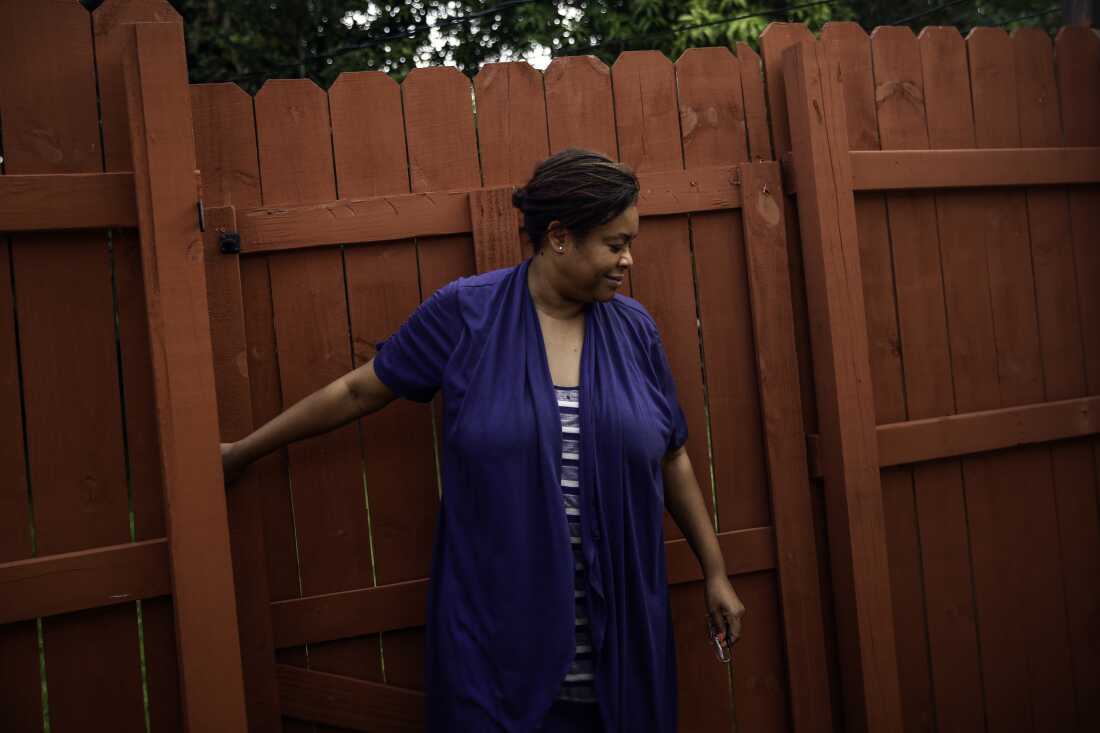 Farah Larrieux pulls a tall wooden gate shut behind her.