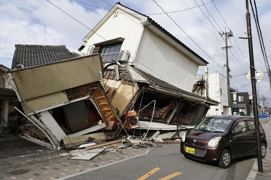 A vehicle passes by collapsed houses after an earthquake in Yatsushiro, Kumamoto prefecture, Wednesday, July 29, 2026.