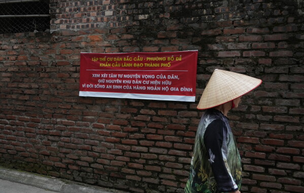 A woman walks past a banner propped up by local residents to call for stopping a project that would displace the entire village by the Red river in Hanoi, Vietnam, Jun 11, 2026. (AP Photo/Hau Dinh)
