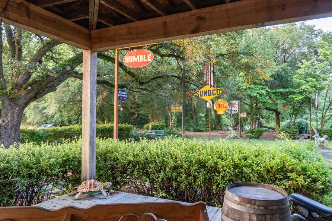Signs that are visible in a yard that has a lot of green trees read: "Shell" "Humble" and "Sunoco."