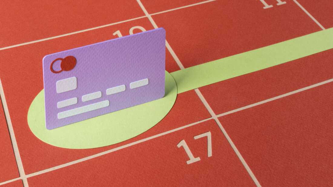 An illustration made of cut paper shows a purple credit card standing up on a flat, red calendar with dates numbered in the grid. A green circle below the card turns into a line that stretches out into the future, demonstrating making a plan to pay off credit card debt. 