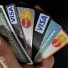 A close-up shows a hand holding various credit cards splayed out.