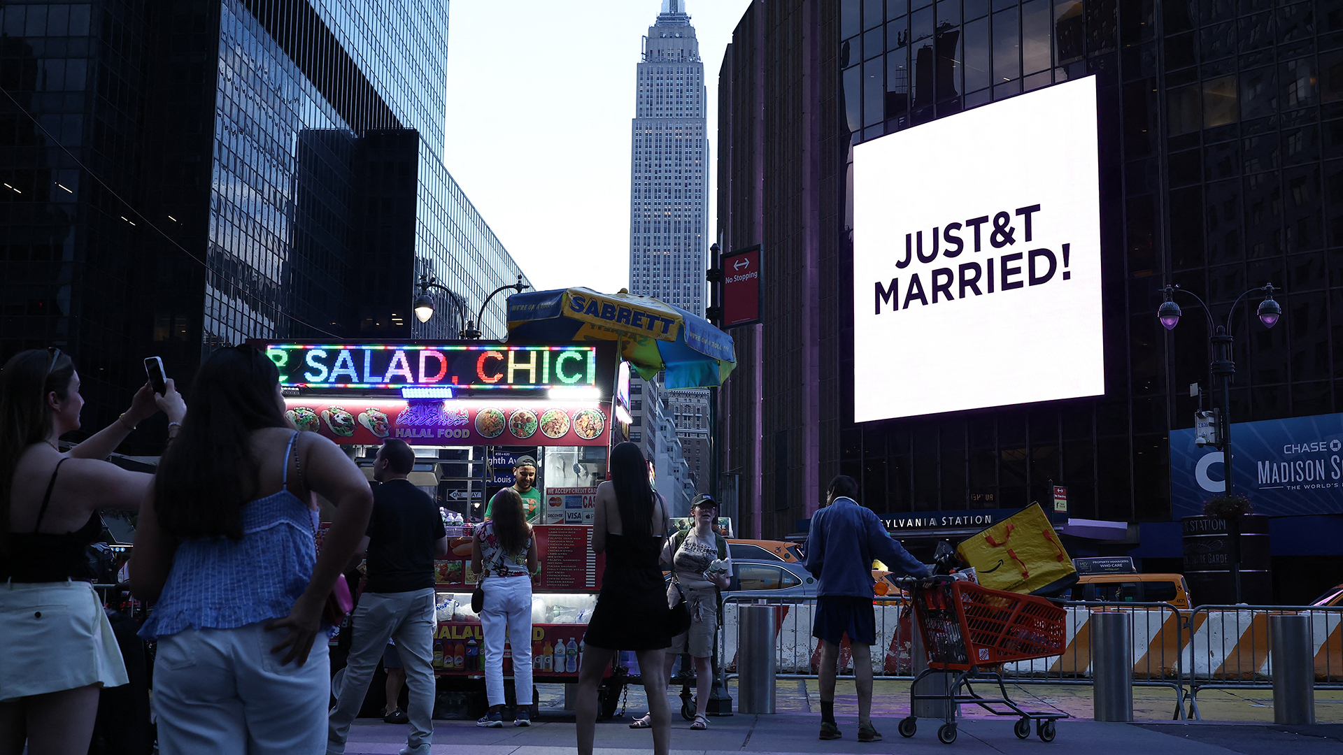 People take photos of a giant screen showing the message "JUST&T MARRIED!" (T&T for Taylor and Travis) outside Madison Square Garden.