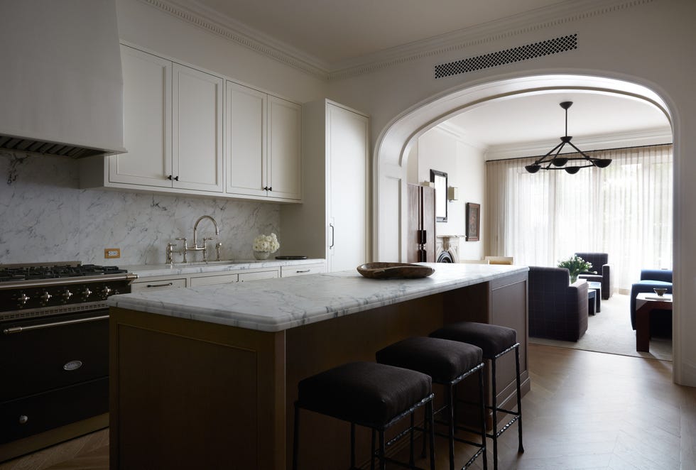 Contemporary kitchen with marble countertops, modern appliances, and an open layout connecting to a living area.