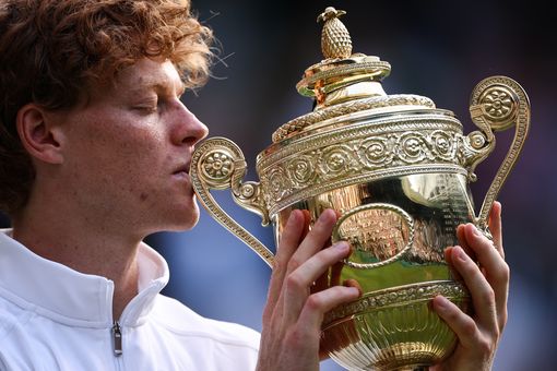 TOPSHOT - Italy's Jannik Sinner kisses the winner's trophy as he poses for pictures following his victory against Spain's Carlos Alcaraz at the end of their men's singles final tennis match on the fourteenth day of the 2025 Wimbledon Championships at The All England Lawn Tennis and Croquet Club in Wimbledon, southwest London, on July 13, 2025. (Photo by HENRY NICHOLLS / AFP) / RESTRICTED TO EDITORIAL USE (Photo by HENRY NICHOLLS/AFP via Getty Images)          