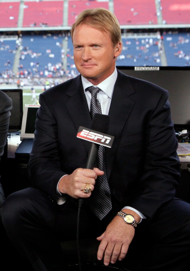 Jon Gruden holding an ESPN microphone at a football game.