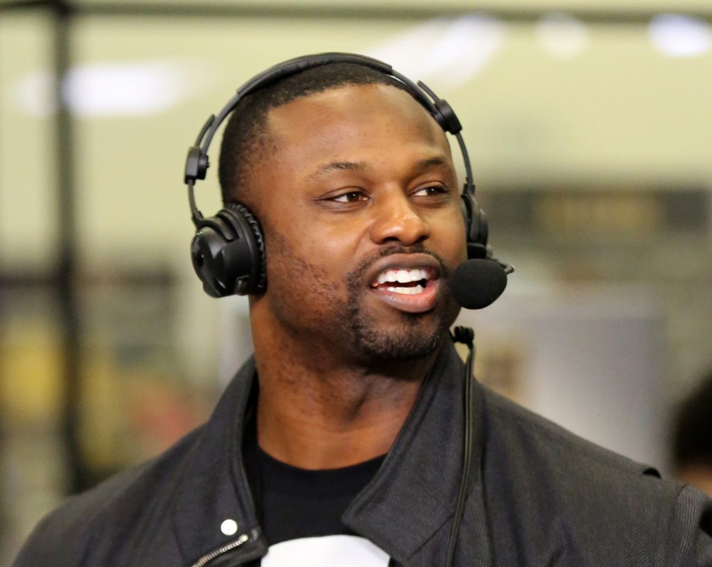 Former NFL player Bart Scott speaking into a microphone while wearing headphones.