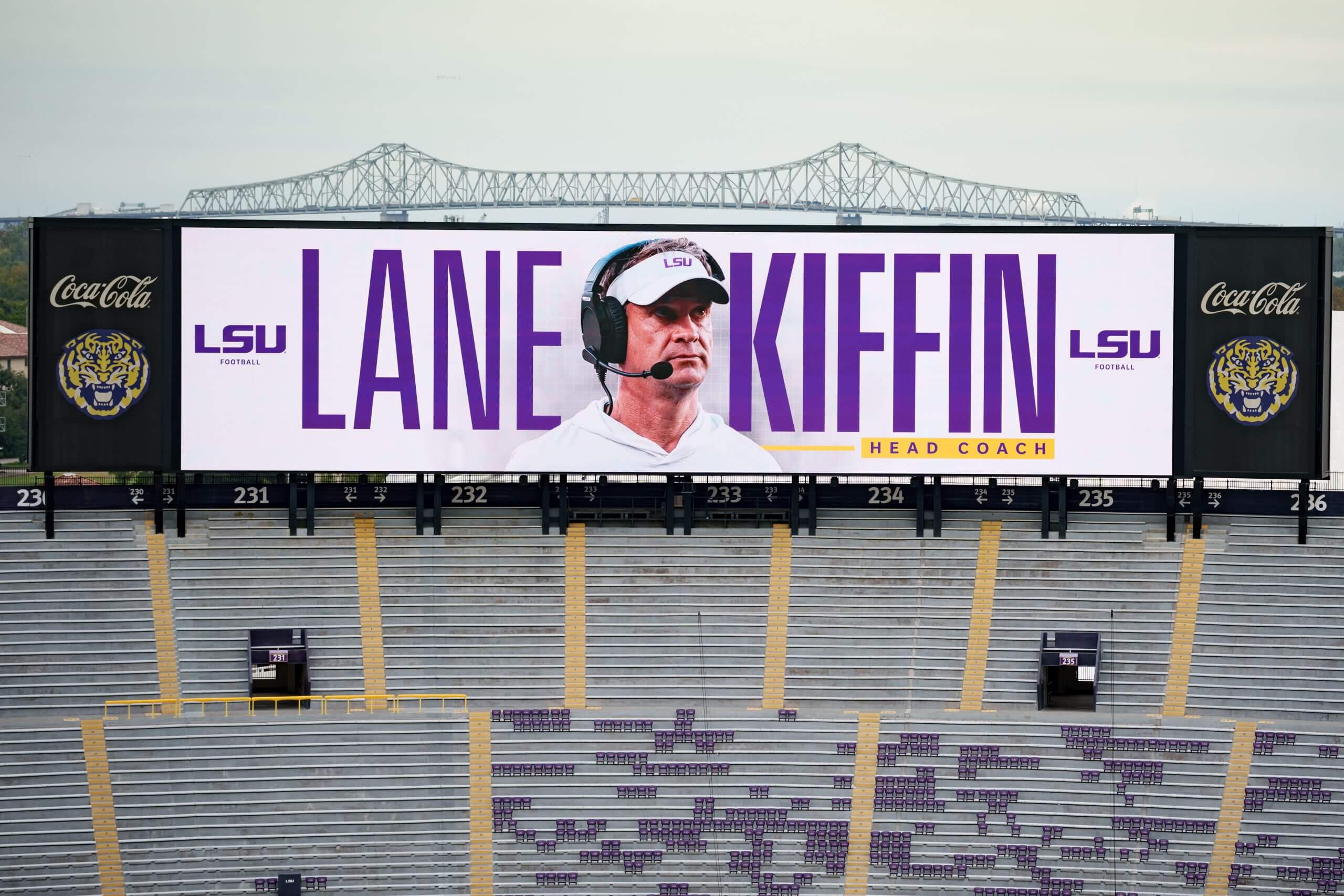A graphic on the scoreboard at LSU's Tiger Stadium featuring Lane Kiffin with a bridge in the background