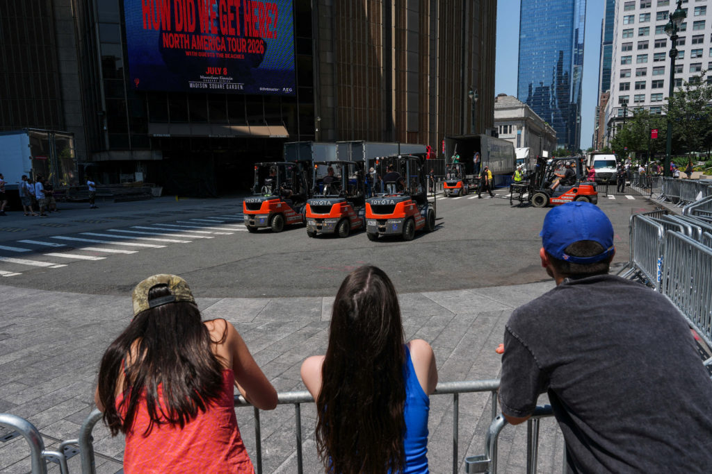 People watch as trucks are unloaded at Madison Square Garden, in New York City