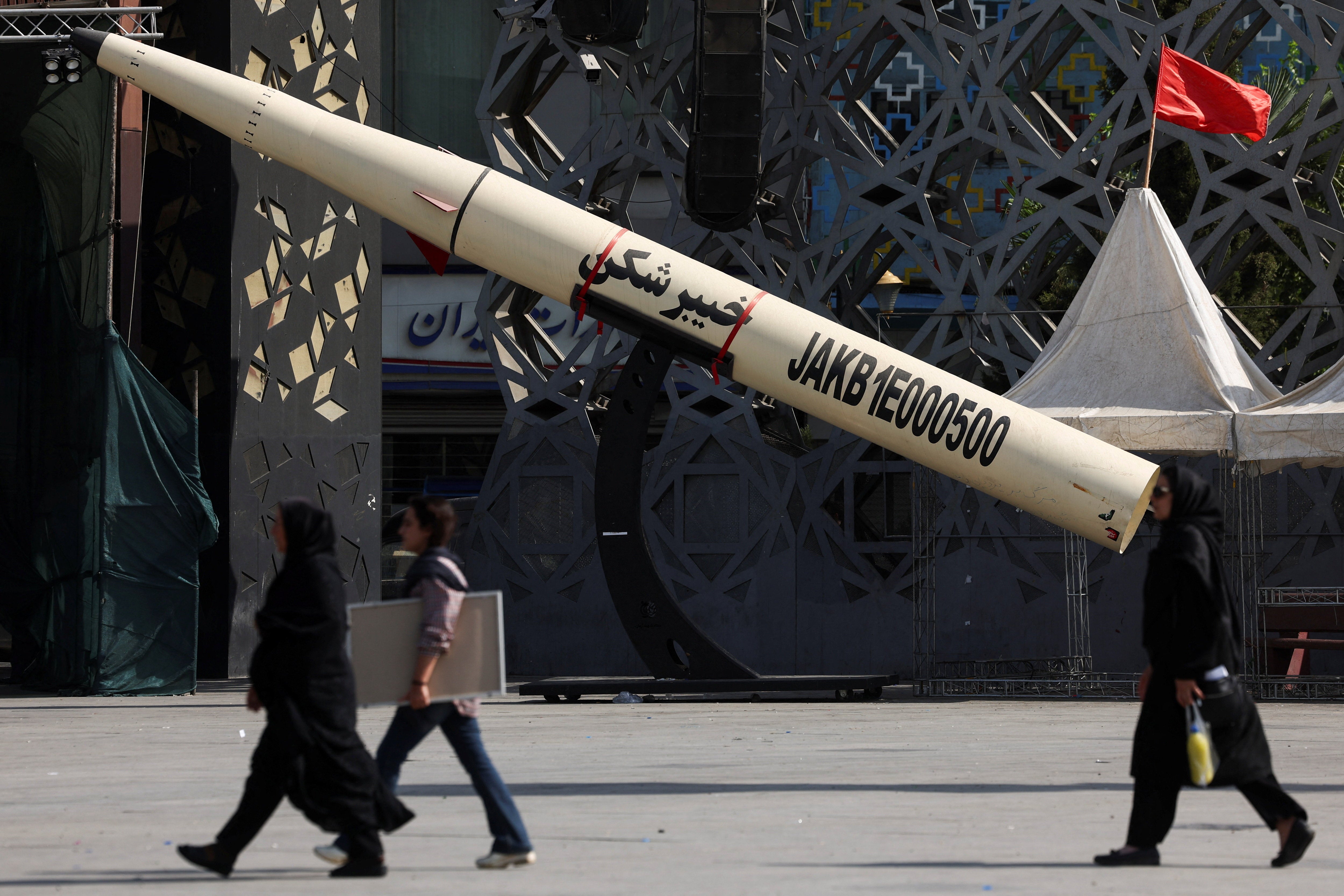 People walk next to a symbolic mockup of an Iranian missile at Imam Hussein Square in Tehran