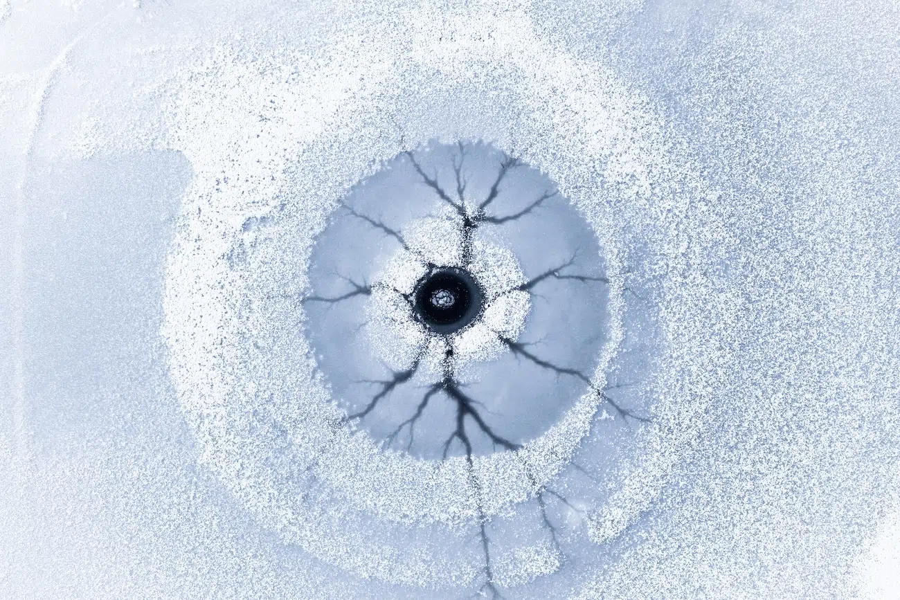 Aerial photograph of a a large, cracking opening in an icy landscape that looks like a human eye.