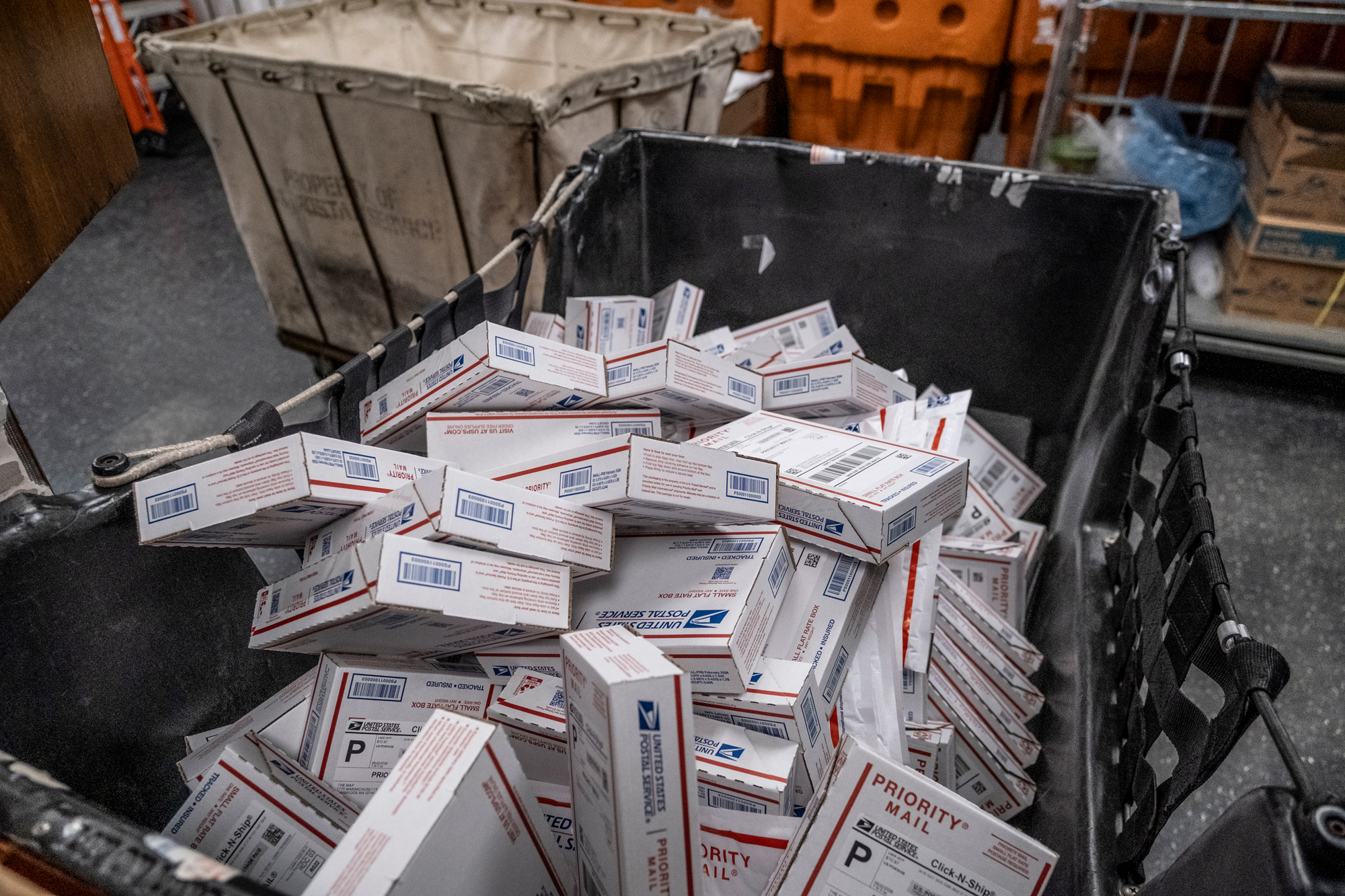 USPS boxes are piled in a large crate to prepare for shipping.