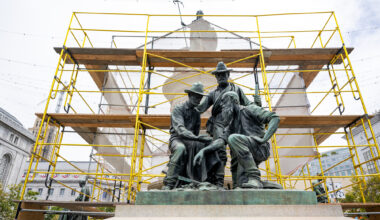 gold-covered scaffolding behind bronze statue of three miners
