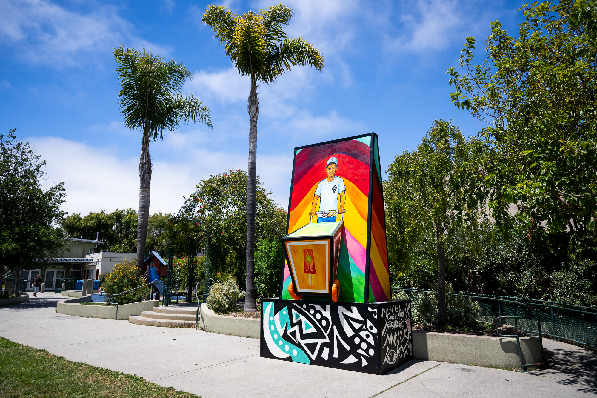 brightly painted wooden monument in park with playground behind
