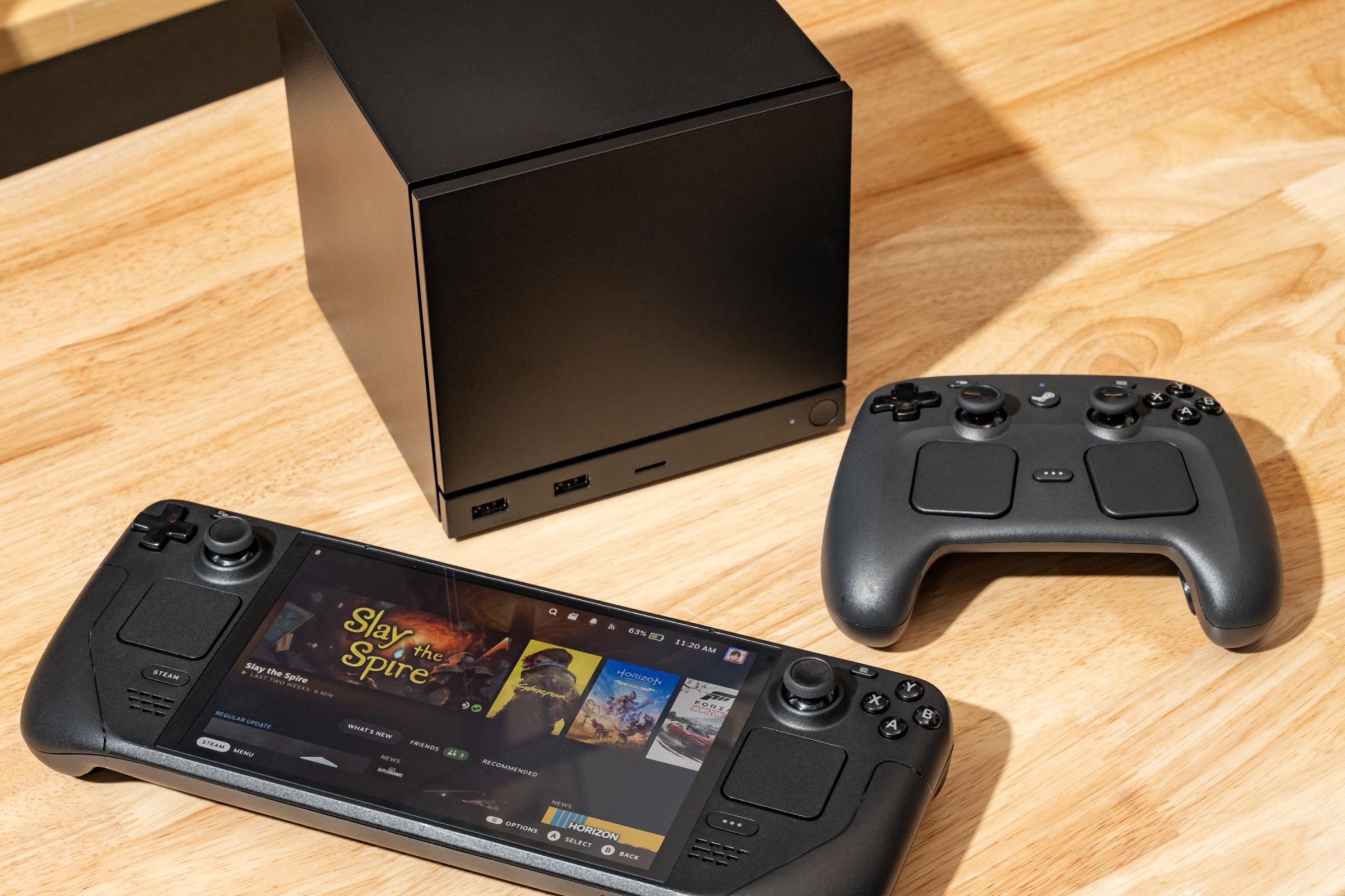 The Steam Machine, Steam Controller, and Steam Deck on a table.