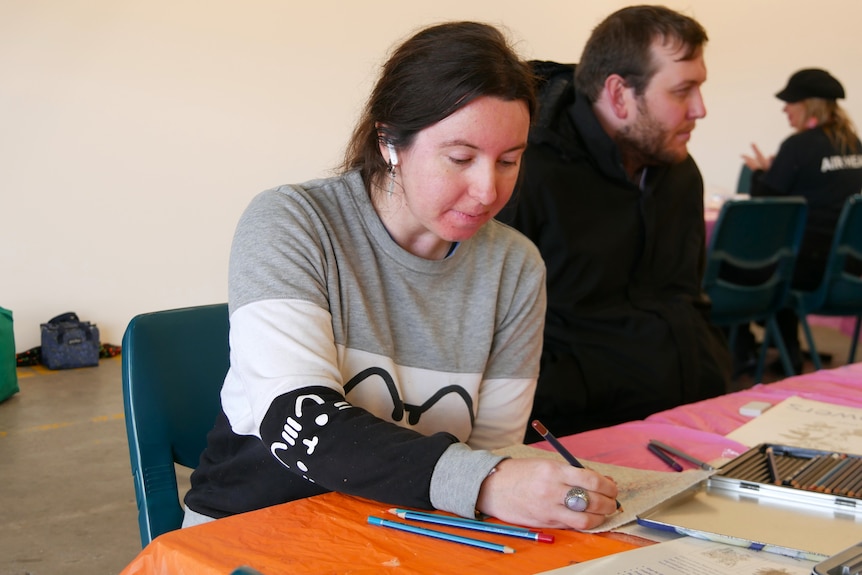 A woman drawing at a table.