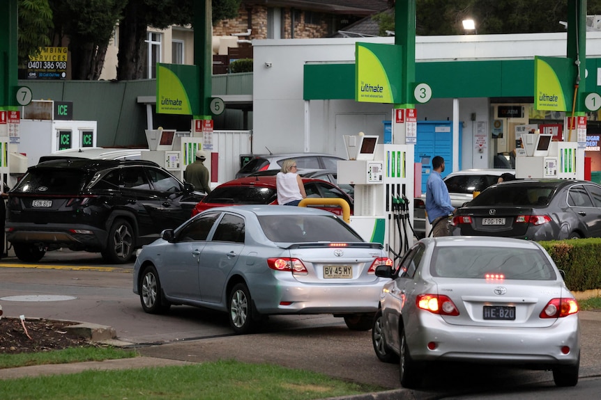 Cars queue at a petrol station.