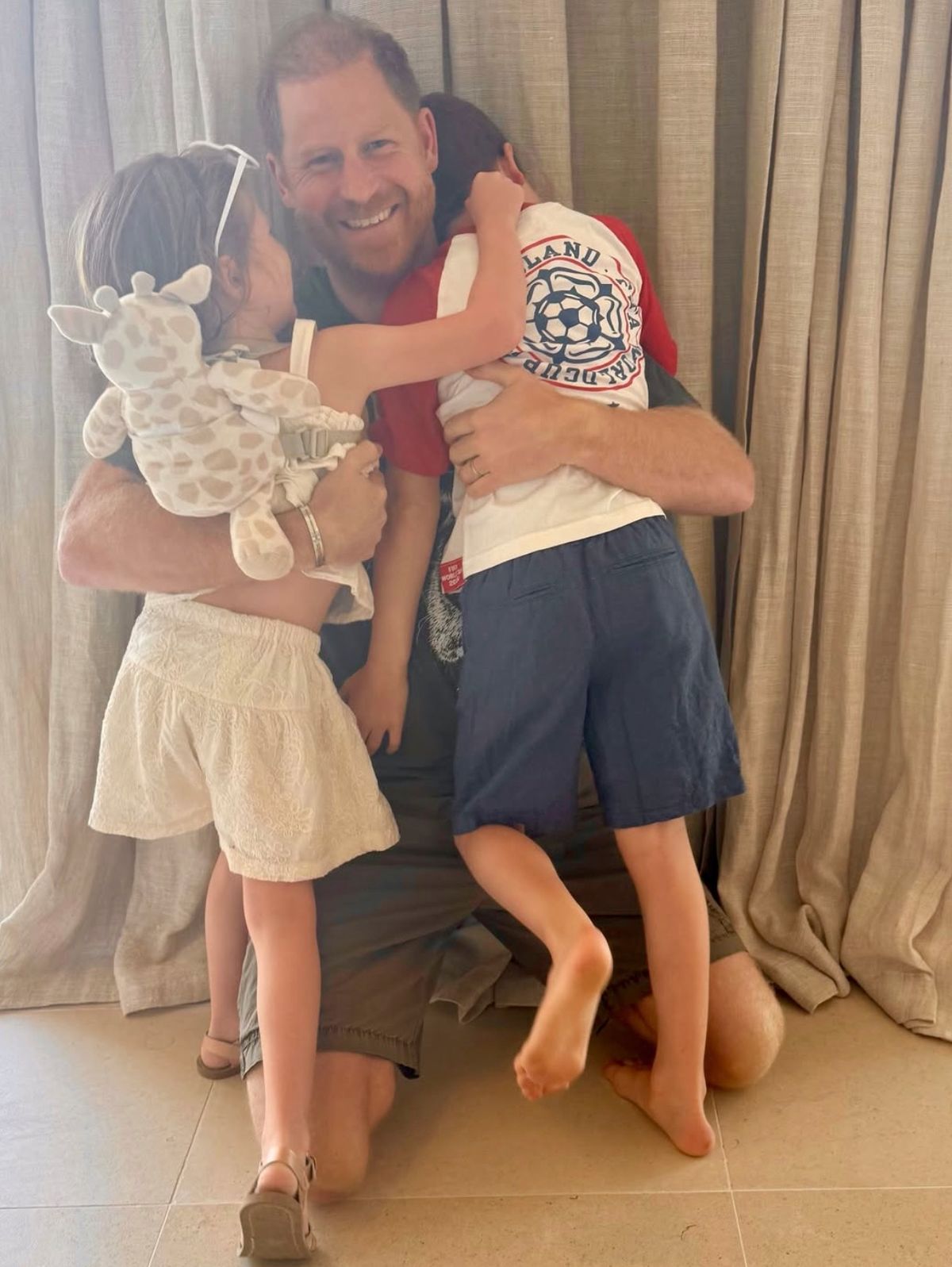 Prince Harry hugging Princess Lilibet and Prince Archie