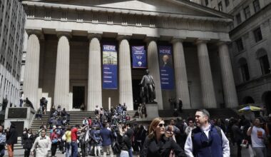 Tourists walk from and congregate on the steps of the Federal Hall National Monument on Wall Street in the Financial District in New York. (AP)