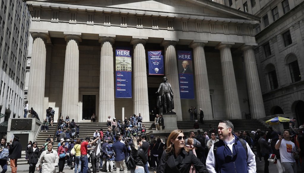 Tourists walk from and congregate on the steps of the Federal Hall National Monument on Wall Street in the Financial District in New York. (AP)
