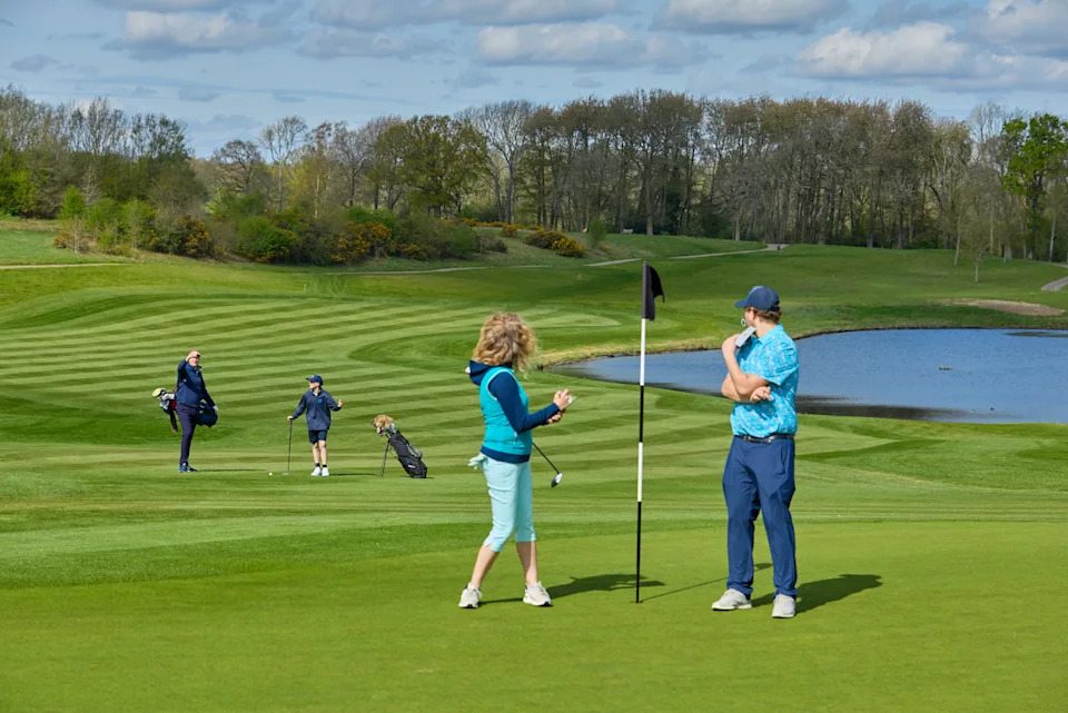 Two golfers not getting off the green quickly after playing which holds up the group behind and impacts pace of play