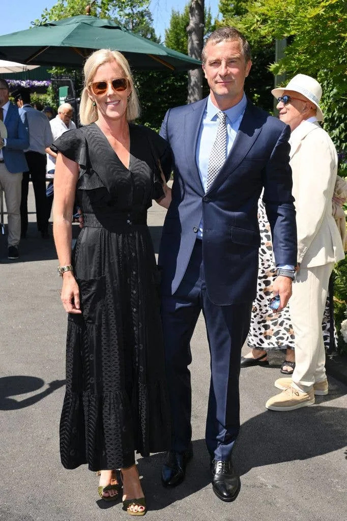 Bear Grylls and wife Shara in black dress standing together at an outdoor event.