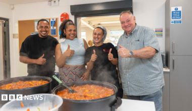 Two young women surrounded by studio lights and tripods selling eyelash serums on a live stream