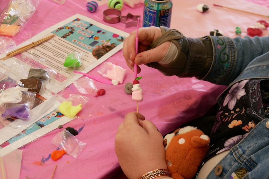 A close-up of hands making pottery beads.
