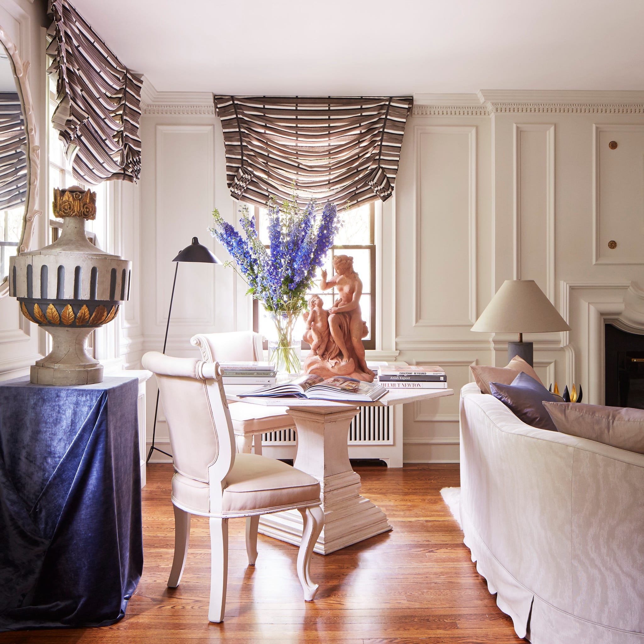 Elegant living room with floral arrangement, sculpture, and refined furniture elements in a bright, airy setting.