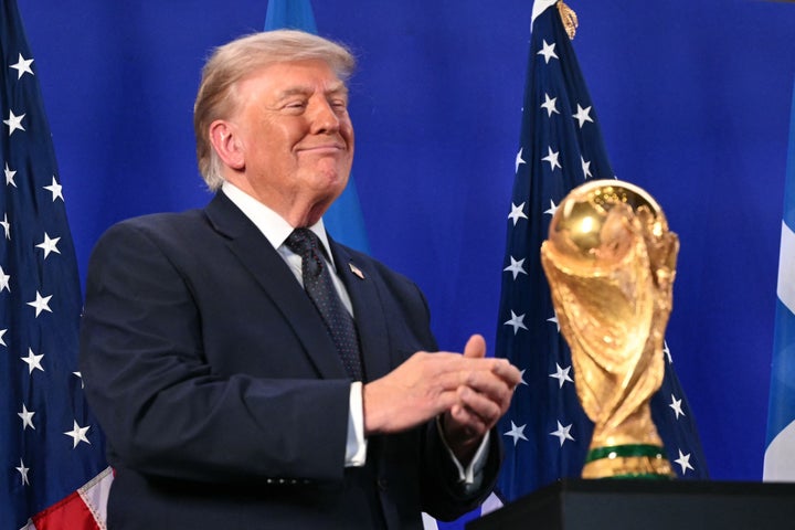 U.S. President Donald Trump stands by the FIFA World Cup Trophy as he listens to FIFA President Gianni Infantino (off frame) speak during a FIFA reception at Trump Tower on Friday in New York City. Trump will attend the 2026 World Cup final between Spain and Argentina. (Photo by Mandel Ngan/AFP via Getty Images)