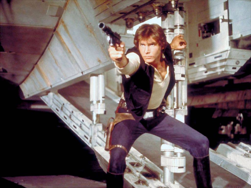 Harrison Ford as Hans Solo crouches and points a laser gun in Episode IV: A New Hope.