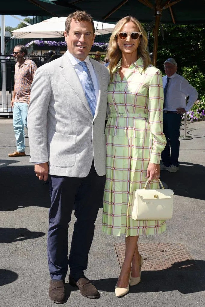 Peter Phillips and Harriet Sperling standing together, both smiling. He wears a light suit, she a green plaid dress and sunglasses.