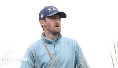 Andrew Wilson playing in The Open Final Qualifier at Dundonald Links, watching his ball as he wears a sky-blue wind-jammer
