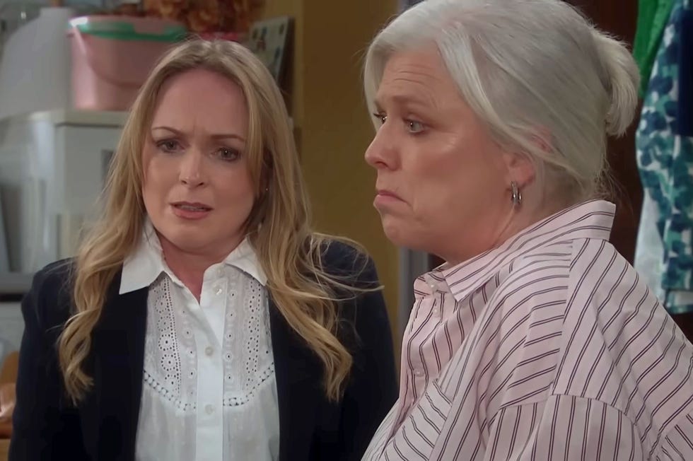 Emmerdale Vanessa Woodfield and Dr Caitlin Todd emmerdale, living vanessa woodfield, wearing a black blazer over a white shirt, sat down and looking upset, with dr caitlin todd in a pale pink striped shirt looks away from her
