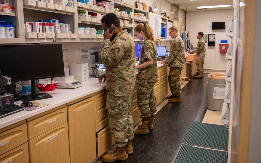 Four airmen at a counter fill prescriptions.