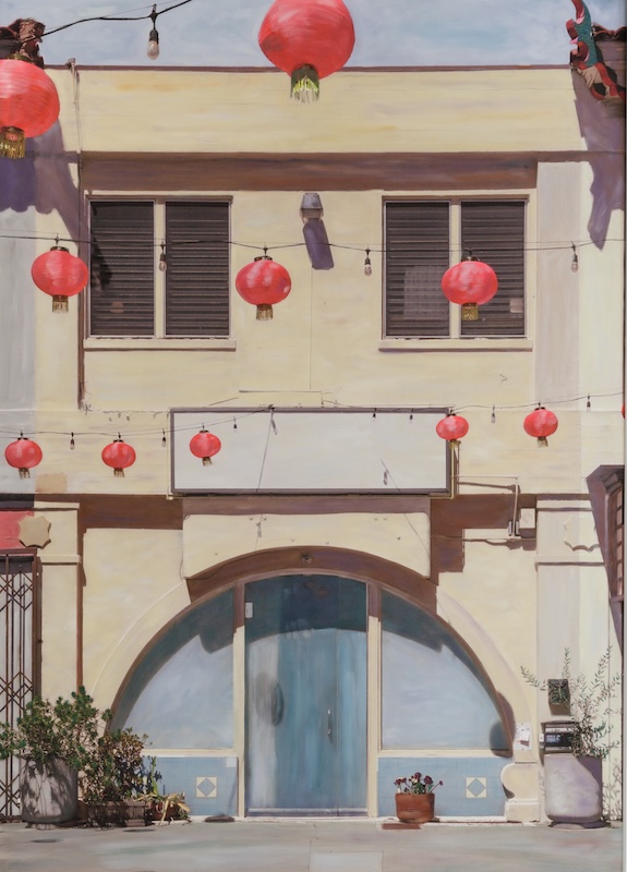 A building façade with red lanterns hanging above a blue arched doorway, © Ann Mitchell.