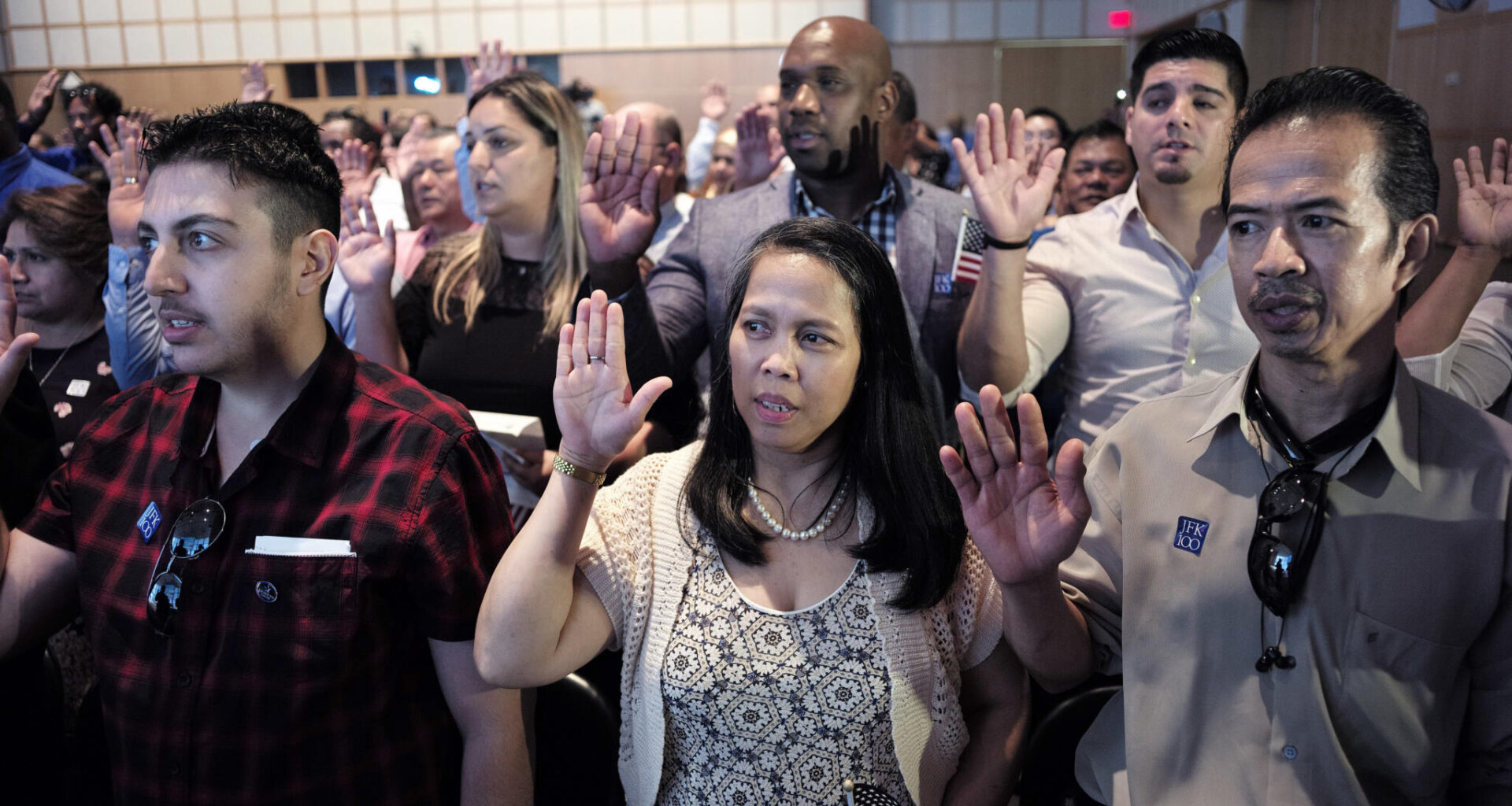 Acharaporn Sundosd, center, originally of Thailand, and a resident of Quincy, Mass., takes the oath of United States citizenship along with others during a naturalization ceremony, Wednesday, July 18, 2018, at the John F. Kennedy Presidential Library and Museum in Boston. (Steven Senne/AP)