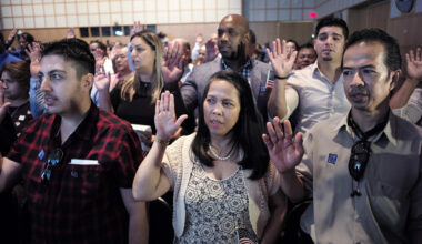 Acharaporn Sundosd, center, originally of Thailand, and a resident of Quincy, Mass., takes the oath of United States citizenship along with others during a naturalization ceremony, Wednesday, July 18, 2018, at the John F. Kennedy Presidential Library and Museum in Boston. (Steven Senne/AP)