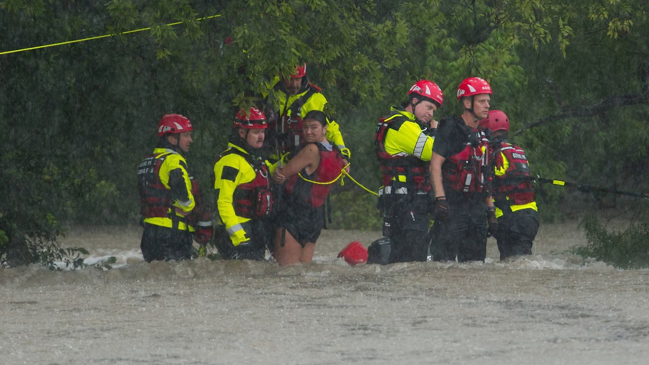 Members of the Boerne Fire Dept. rescue a woman from flood waters on Wednesday, July 15, 2026, in Boerne, Texas. (AP Photo/Darren Abate)