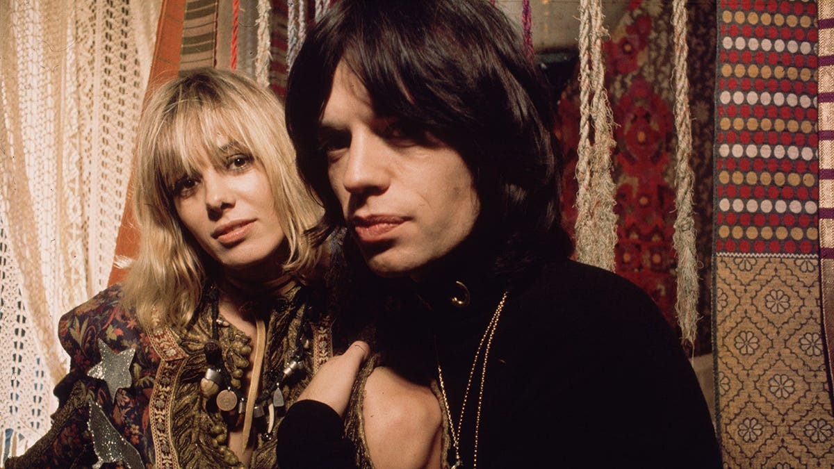 Anita Pallenberg being embraced by Mick Jagger on the set of 