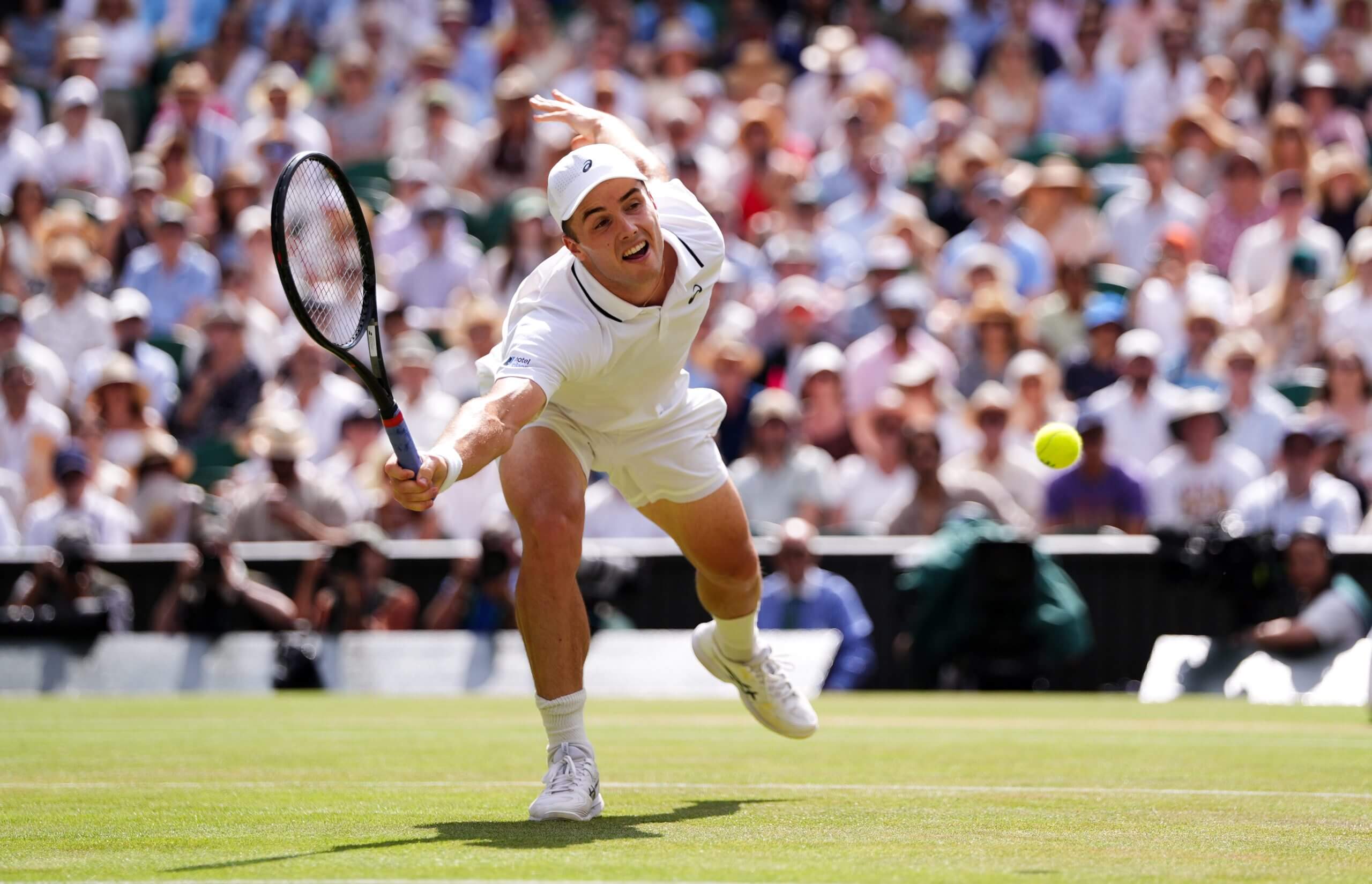 Arthur Féry dives for a forehand volley on a grass court.