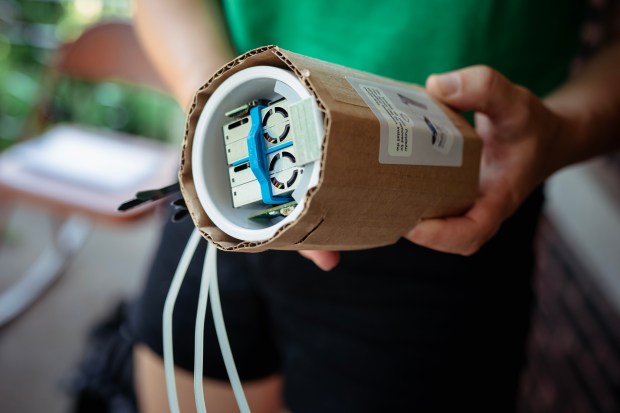 Sonia Monet Saxon, community science organizer at Neighbors for Environmental Justice, installs an air quality monitor at a home in the McKinley Park neighborhood, July 15, 2026. (E. Jason Wambsgans/Chicago Tribune)