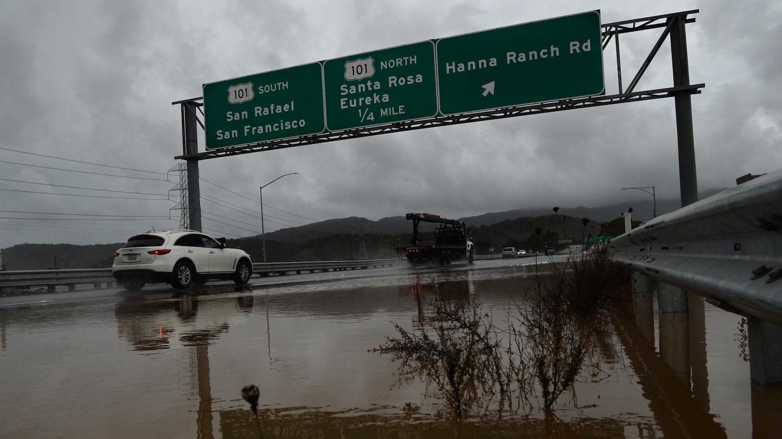 Traffic splashes through a flooded California Highway 37.