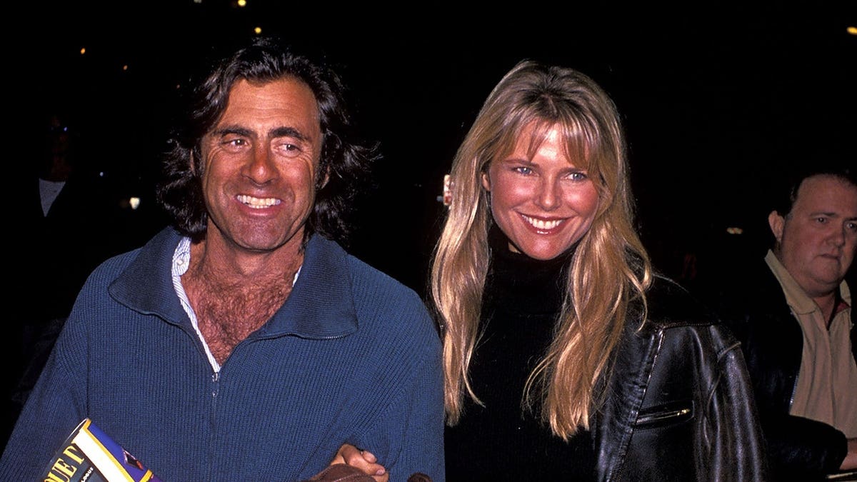 Christie Brinkley and Ricky Taubman smiling and walking together at the Santa Monica Pier.